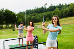 Eine Gruppe von Menschen spielt Golf auf einem grünen Golfplatz.
