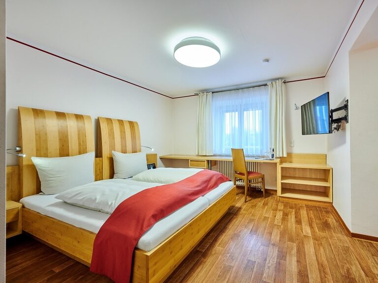 Ein komfortables Bett im Schlafzimmer eines Appartements des Gästehaus Wenisch mit eleganter Innenausstattung.